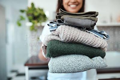 Buy stock photo Closeup shot of a young woman holding a pile of folded laundry at home