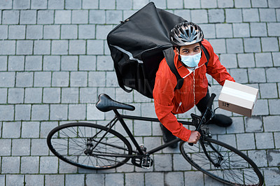 Buy stock photo Shot of a masked man out with his bicycle to do a delivery