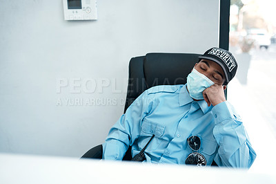 Buy stock photo Shot of a masked young security guard sleeping at a desk in an office