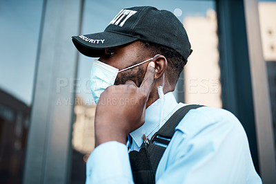 Buy stock photo Shot of a masked young security guard using an earpiece while on patrol outdoors