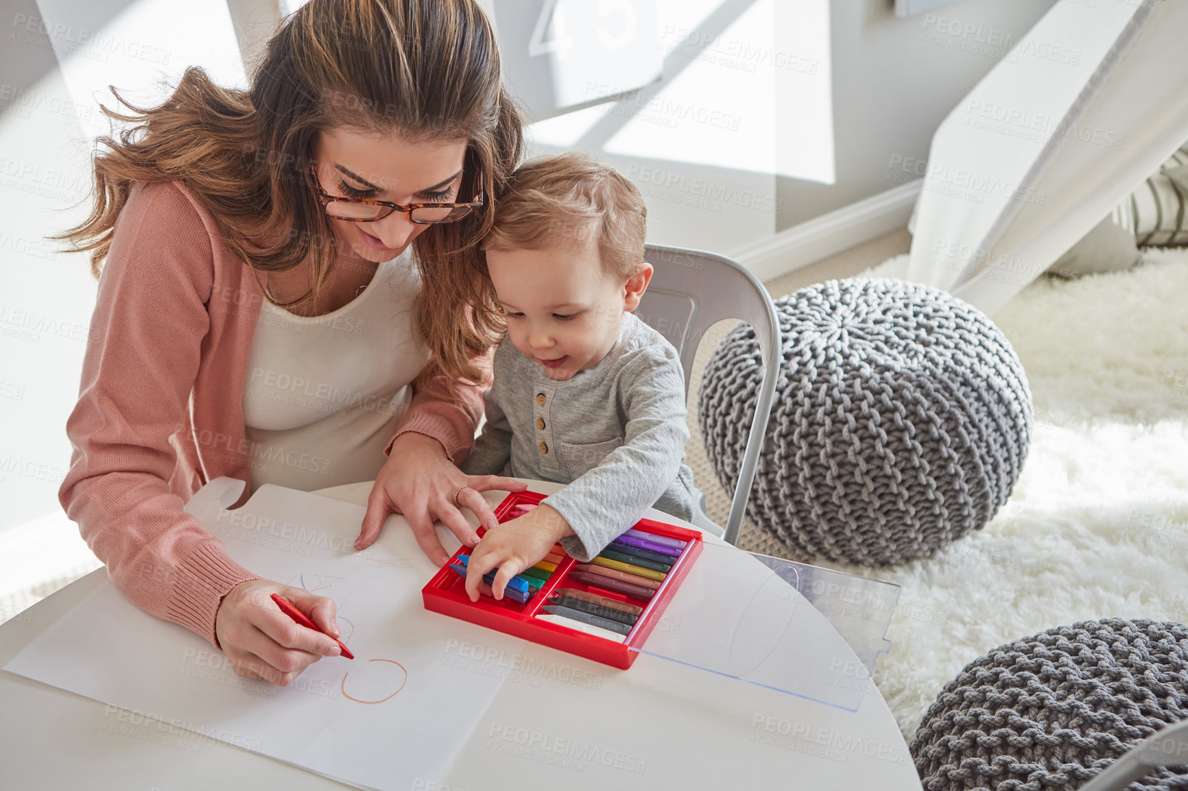 Buy stock photo Shot of a woman and her young son using crayons to draw at home