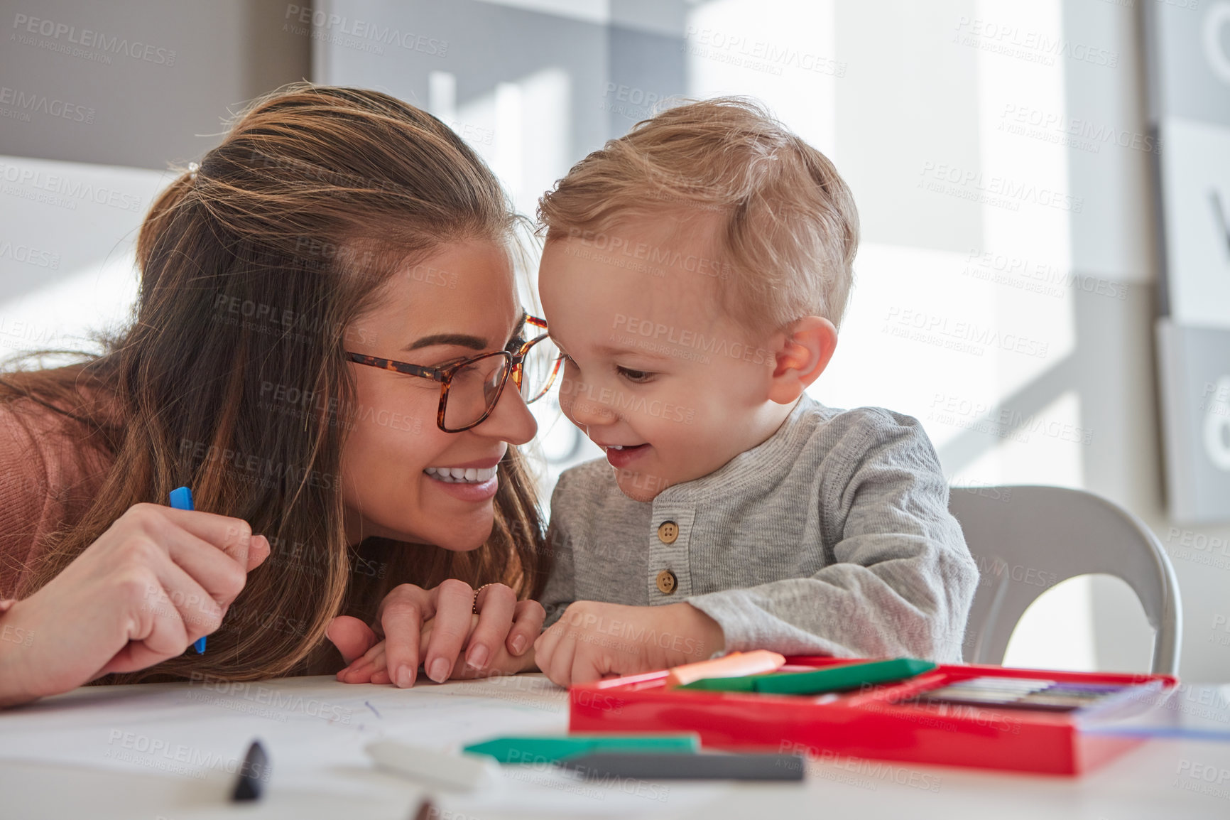 Buy stock photo Shot of a woman and her young son using crayons to draw at home