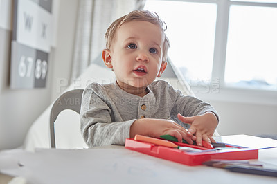 Buy stock photo Cropped shot of a little boy playing with his crayons at home