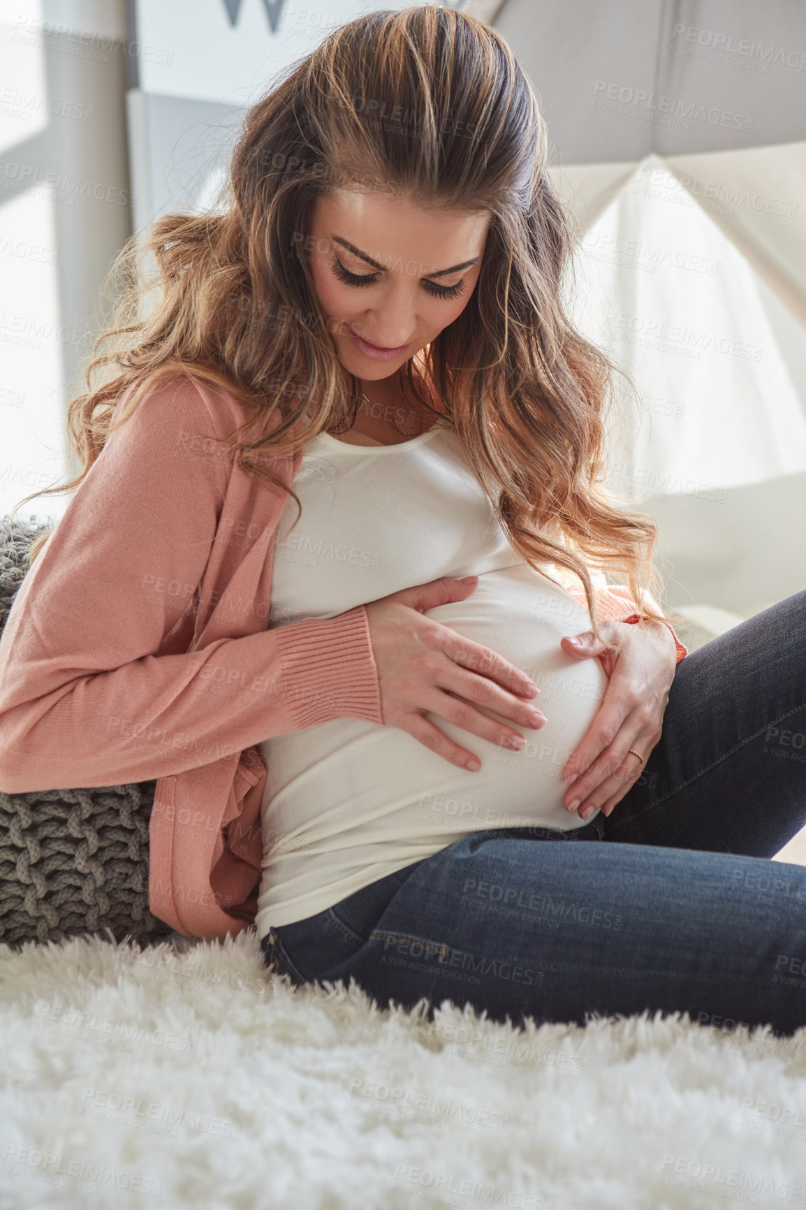 Buy stock photo Shot of a pregnant woman touching her belly while sitting at home