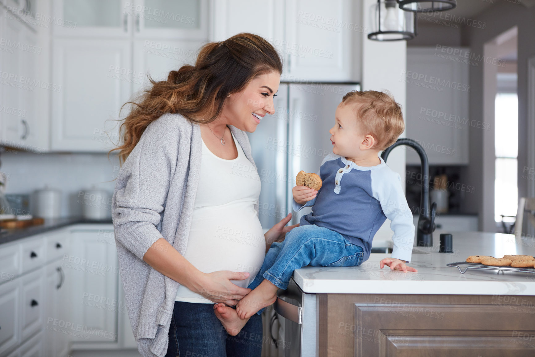 Buy stock photo Shot of a pregnant woman and her son spending time together in the kitchen at home