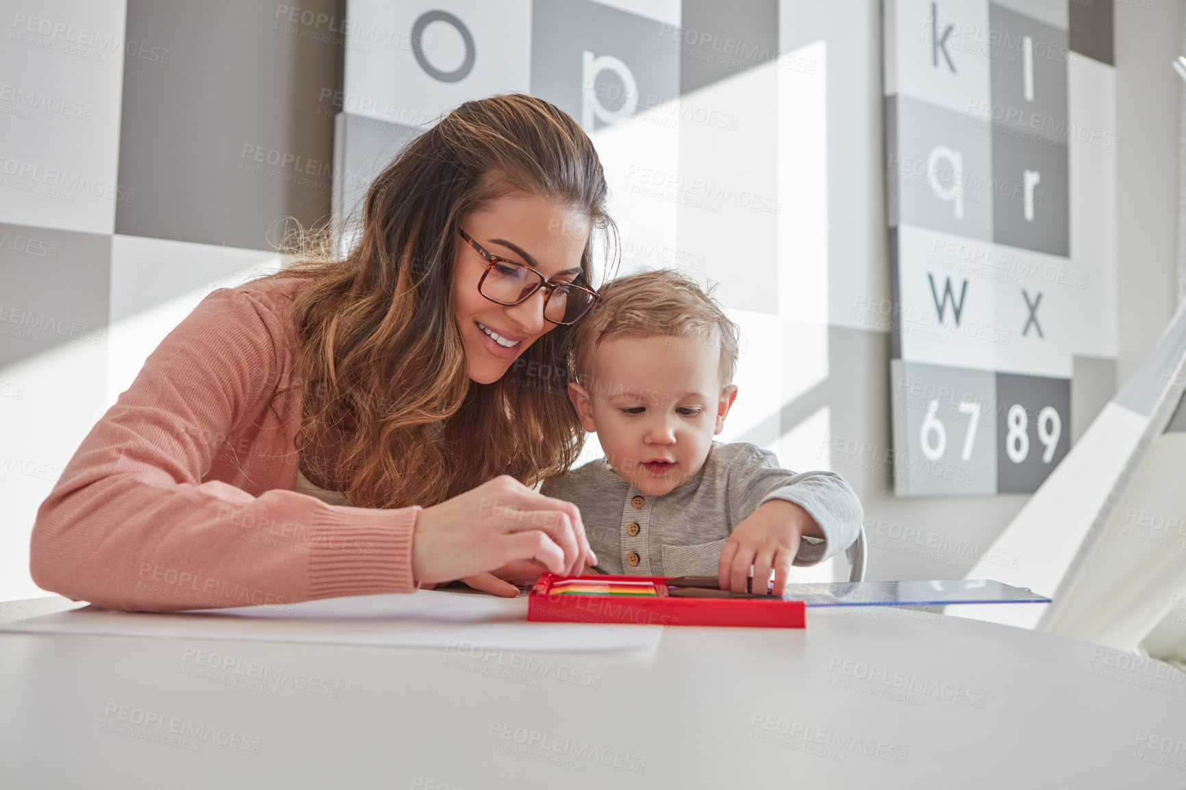 Buy stock photo Shot of a woman and her young son using crayons to draw at home