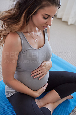 Buy stock photo Shot of a pregnant young woman practicing a yoga routine at home