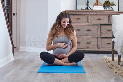 Buy stock photo Shot of a pregnant young woman practicing a yoga routine at home
