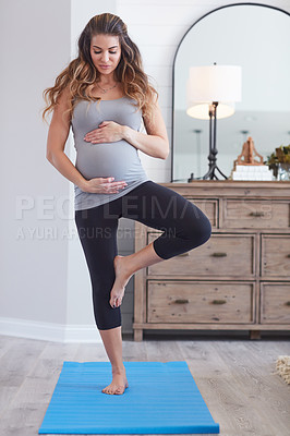 Buy stock photo Shot of a pregnant young woman practicing the tree pose during a yoga routine at home