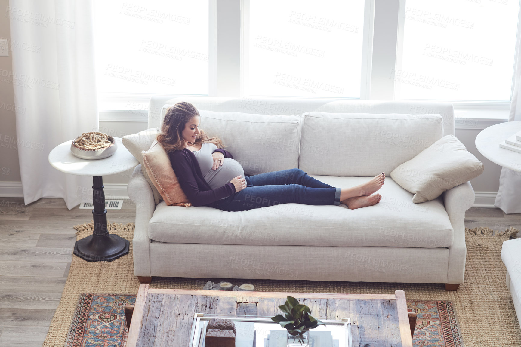 Buy stock photo Full length shot of an attractive young pregnant woman relaxing on the sofa at home