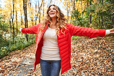Buy stock photo Cropped shot of an attractive young woman standing with her arms outstretched in the forest during autumn