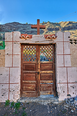 Buy stock photo Old abandoned church or cathedral with a weathered wall and broken wooden door. Vintage and aged religious building built in a traditional architectural style or design with a crucifix for faith