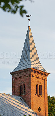 Buy stock photo Tall infrastructure and tower used to symbolize faith and Christian or Catholic devotion. Architecture roof design of church steeple and spire on gothic style cathedral building against blue sky.