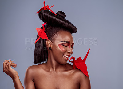 Buy stock photo Studio shot of a beautiful young woman wearing Asian inspired makeup and posing with origami against a grey background