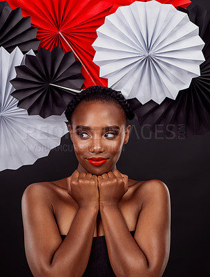 Buy stock photo Beauty, thinking and black woman with origami fans in studio, smile and dark background. Face, makeup and cosmetics of female model with pride, traditional Japanese and paper art for culture hat