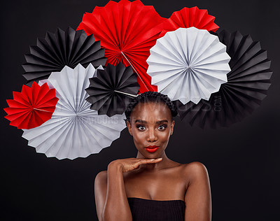 Buy stock photo Face, aesthetic and black woman with origami fans in studio isolated on a dark background. Beauty portrait, makeup cosmetics and skincare of female model with traditional Japanese art for fashion hat