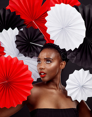 Buy stock photo African woman, makeup and paper for fans in studio for creative beauty or cosmetics for glamour with elegance in black background. Female person, skincare and treatment or glow with origami art