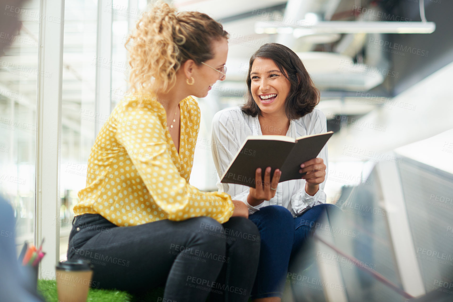 Buy stock photo Shot of two young businesswomen having a discussion in a modern office