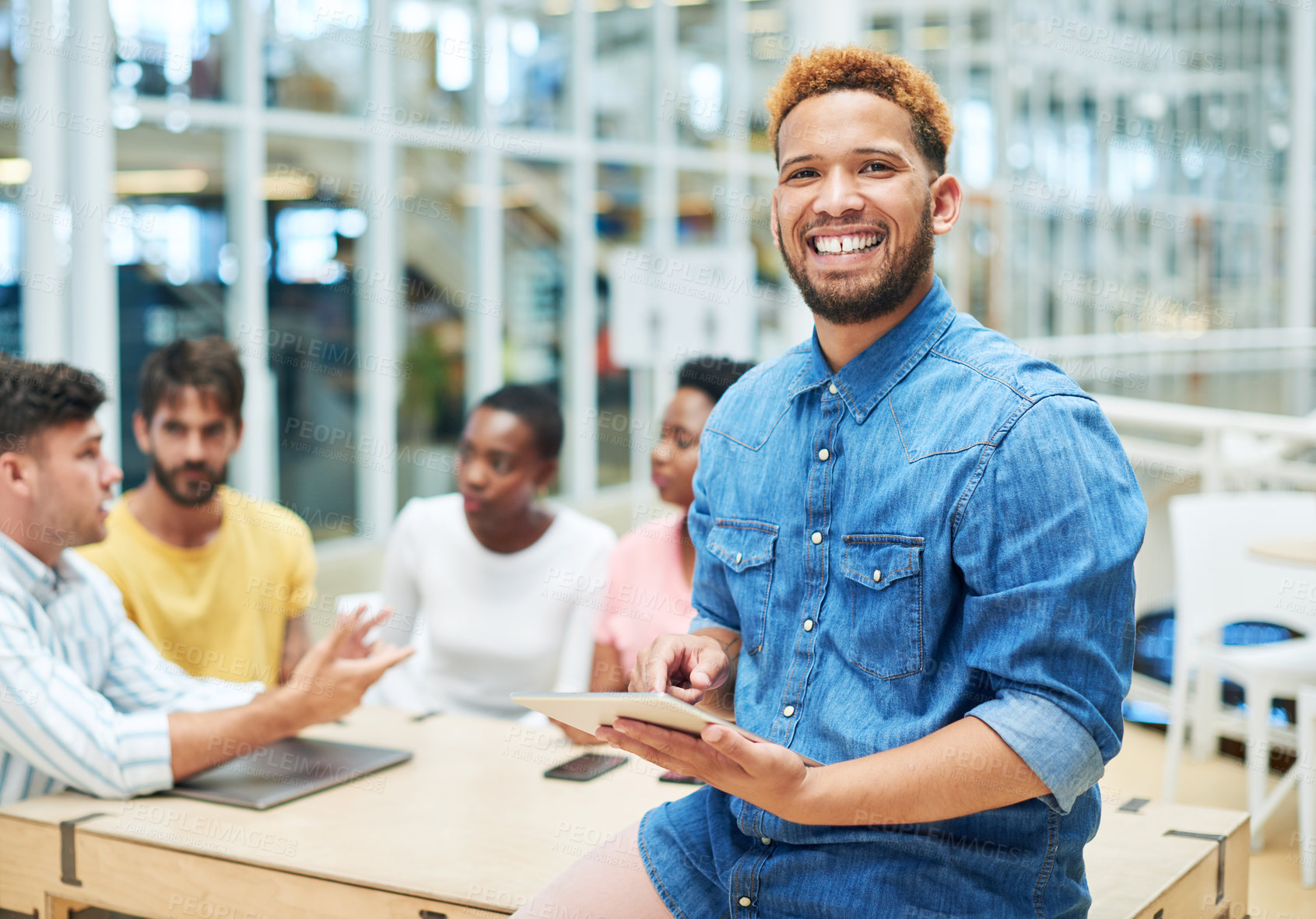 Buy stock photo Shot of a young businessman using a digital tablet during a team meeting in a modern office