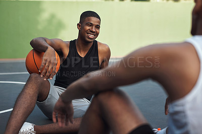 Buy stock photo Shot of two sporty young men chatting to each other on a basketball court