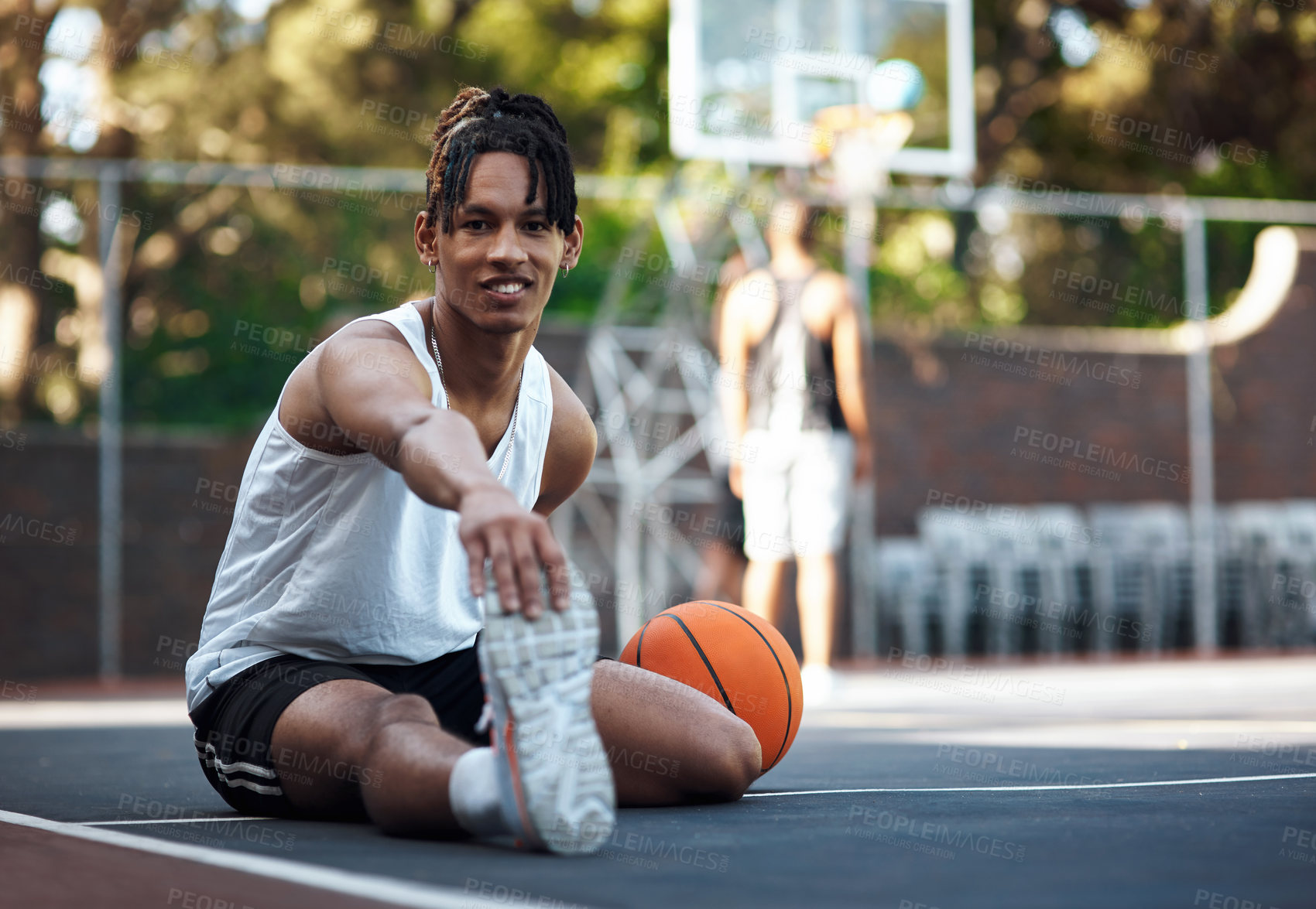 Buy stock photo Portrait of a sporty young man stretching his legs on a basketball court