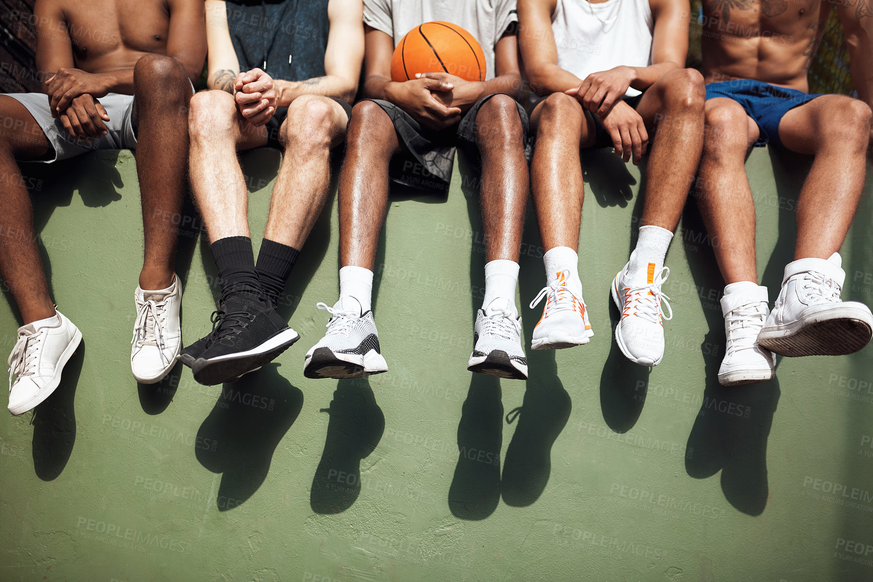 Buy stock photo Closeup shot of a group of sporty young men sitting on a wall on a sports court