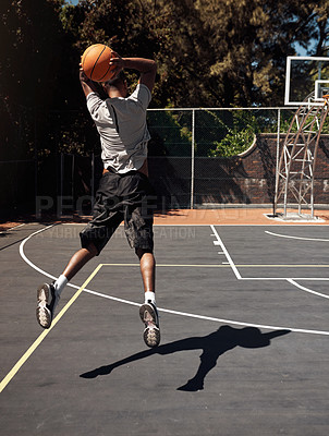 Buy stock photo Rearview shot of a sporty young man throwing a basketball into a net on a sports court