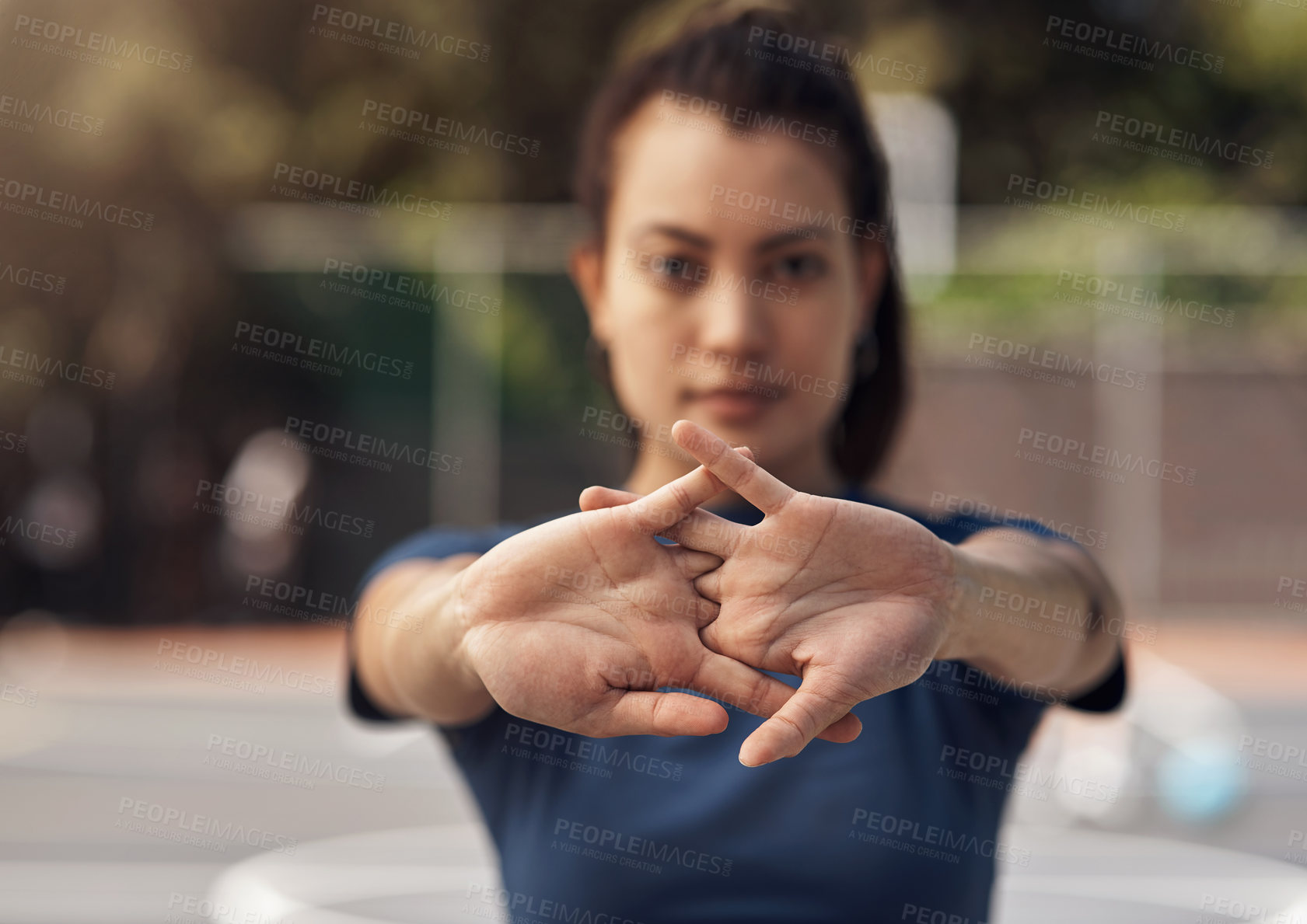 Buy stock photo Portrait of a sporty young woman stretching her arms on a sports court