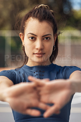 Buy stock photo Portrait of a sporty young woman stretching her arms on a sports court