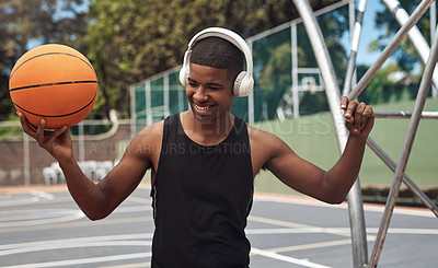 Buy stock photo Shot of a sporty young man listening to music while playing basketball on a sports court
