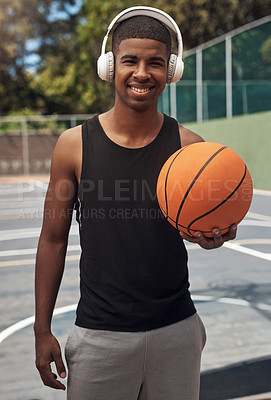 Buy stock photo Portrait of a sporty young man listening to music while playing basketball on a sports court