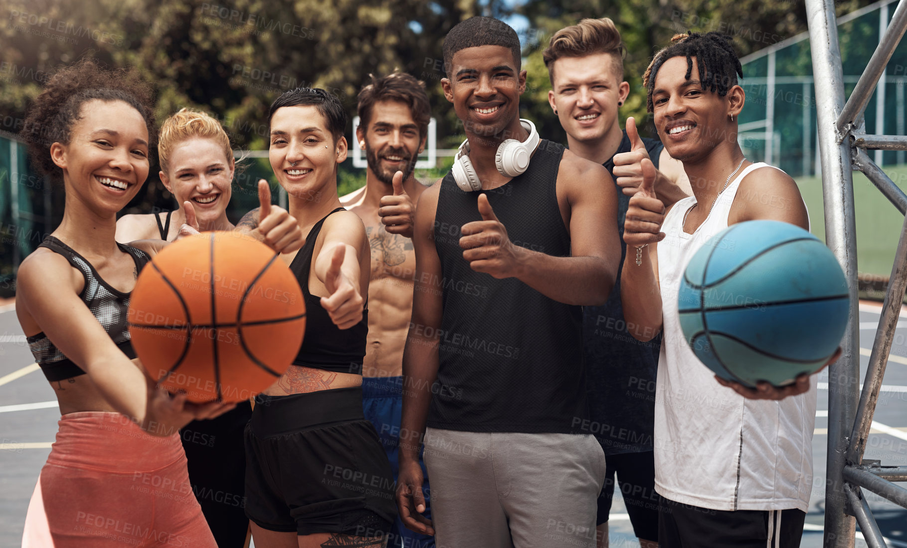 Buy stock photo Portrait of a group of sporty young people showing thumbs up while standing together on a sports court