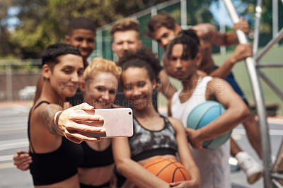 Buy stock photo Shot of a group of sporty young people taking selfies together on a sports court