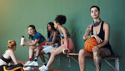Buy stock photo Cropped portrait of an attractive young female athlete sitting on a bench at the basketball court with her teammates in the background