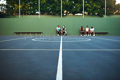 Buy stock photo Shot of a group of sporty young men sitting on a basketball court