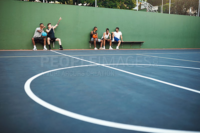 Buy stock photo Shot of a group of sporty young men sitting on a basketball court