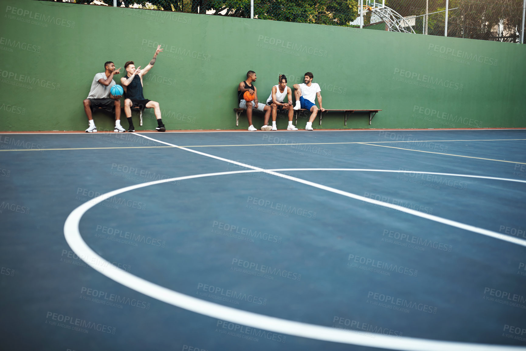 Buy stock photo Shot of a group of sporty young men sitting on a basketball court