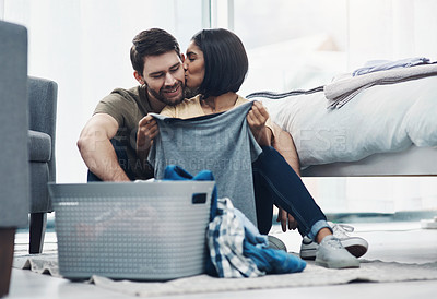 Buy stock photo Shot of an affectionate young couple doing laundry together at home