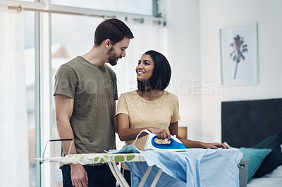 Buy stock photo Shot of a happy young couple ironing freshly washed laundry together at home