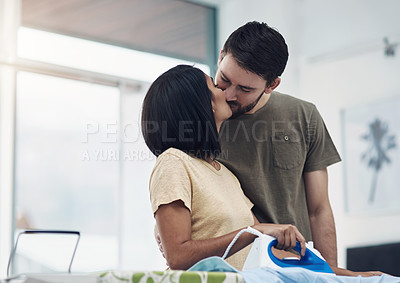 Buy stock photo Shot of a happy young couple ironing freshly washed laundry together at home