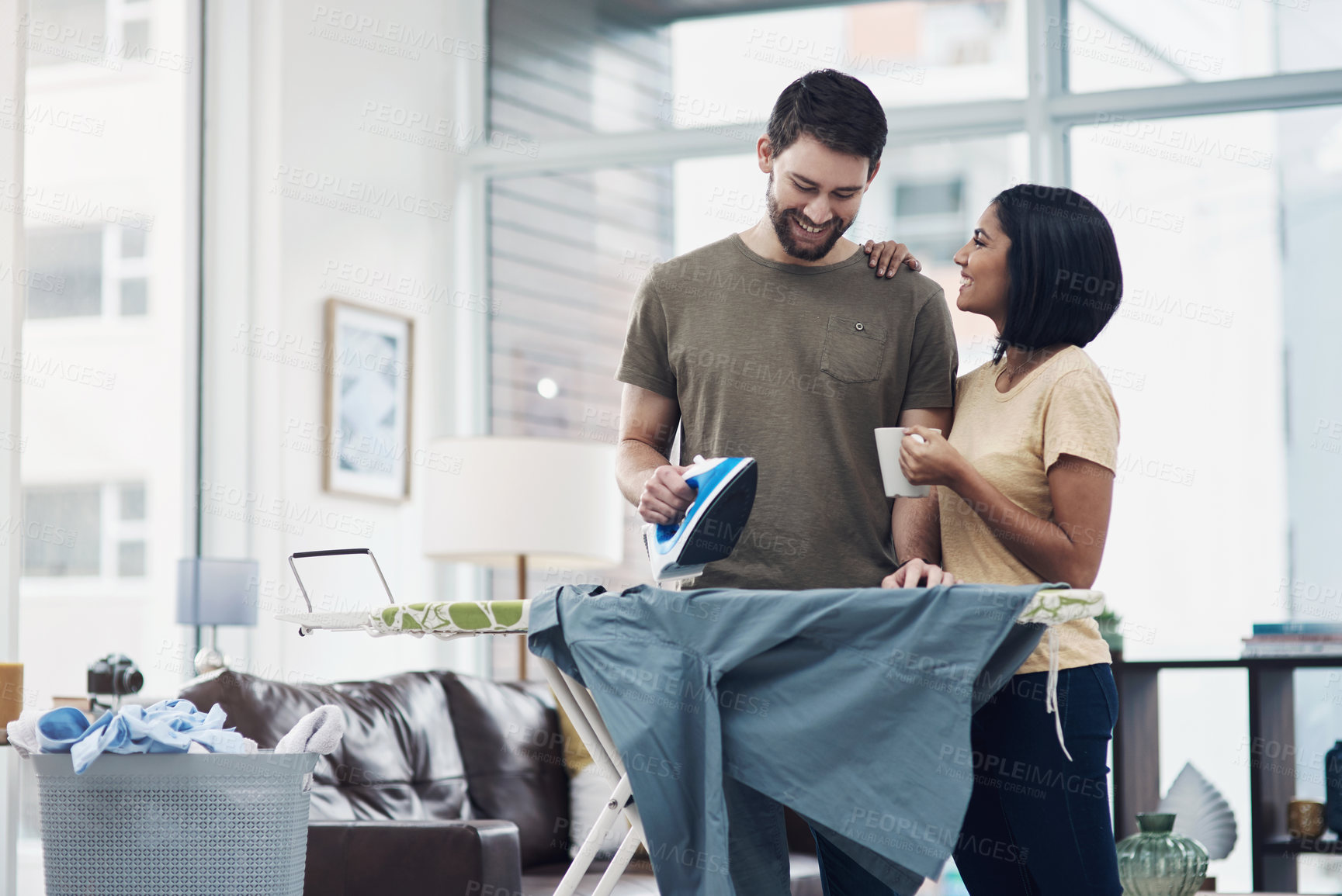 Buy stock photo Shot of a happy young couple ironing freshly washed laundry together at home