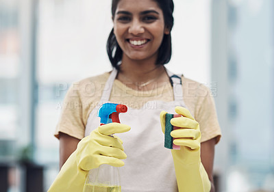 Buy stock photo Shot of a young woman using rubber gloves and disinfectant to clean her home
