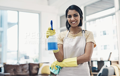 Buy stock photo Shot of a young woman using rubber gloves and disinfectant to clean her home