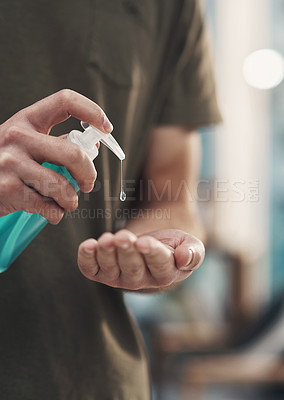 Buy stock photo Shot of an unrecognisable man disinfecting his hands with sanitiser at home