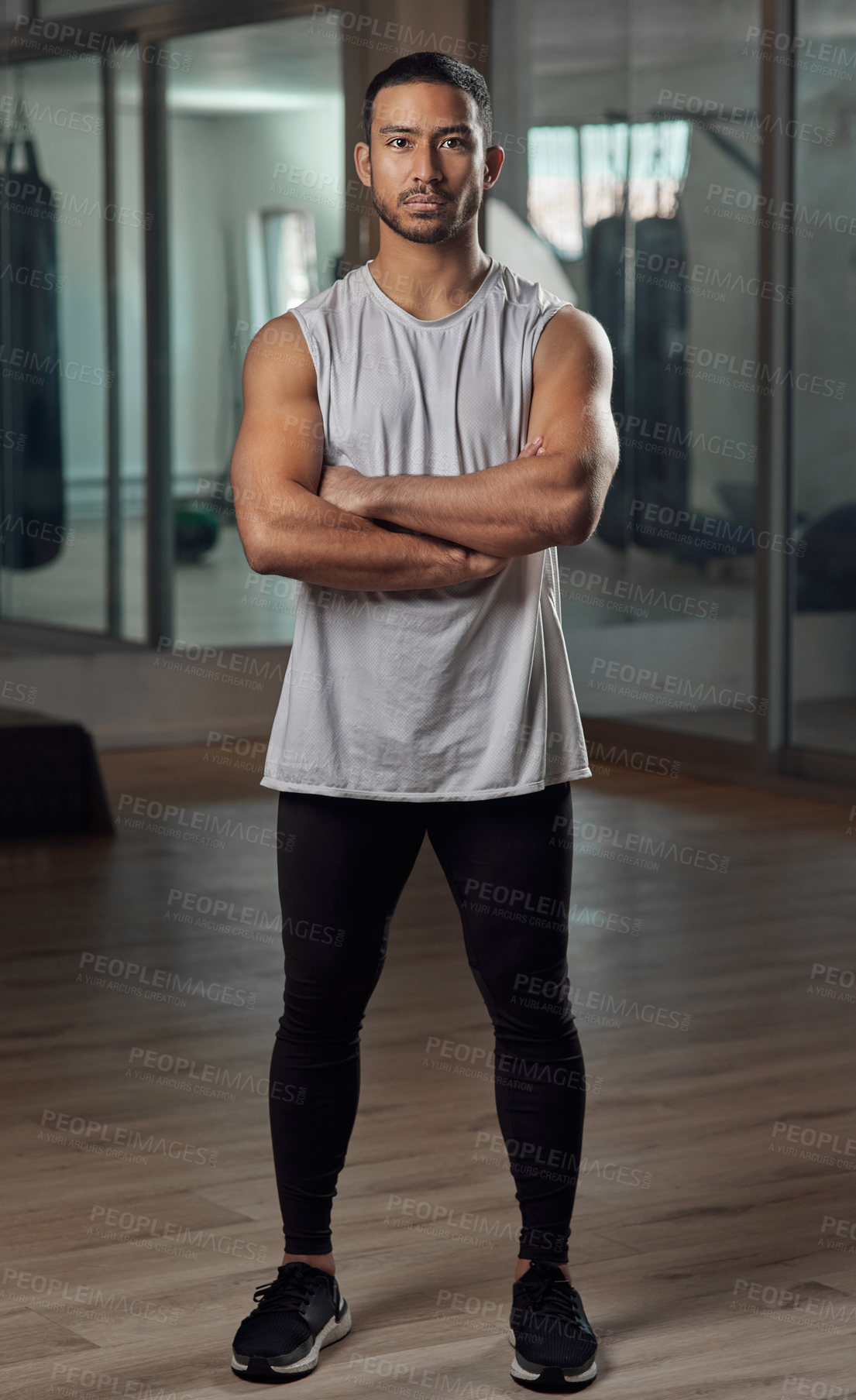 Buy stock photo Full length portrait of a handsome young male athlete standing with his arms crossed in the gym