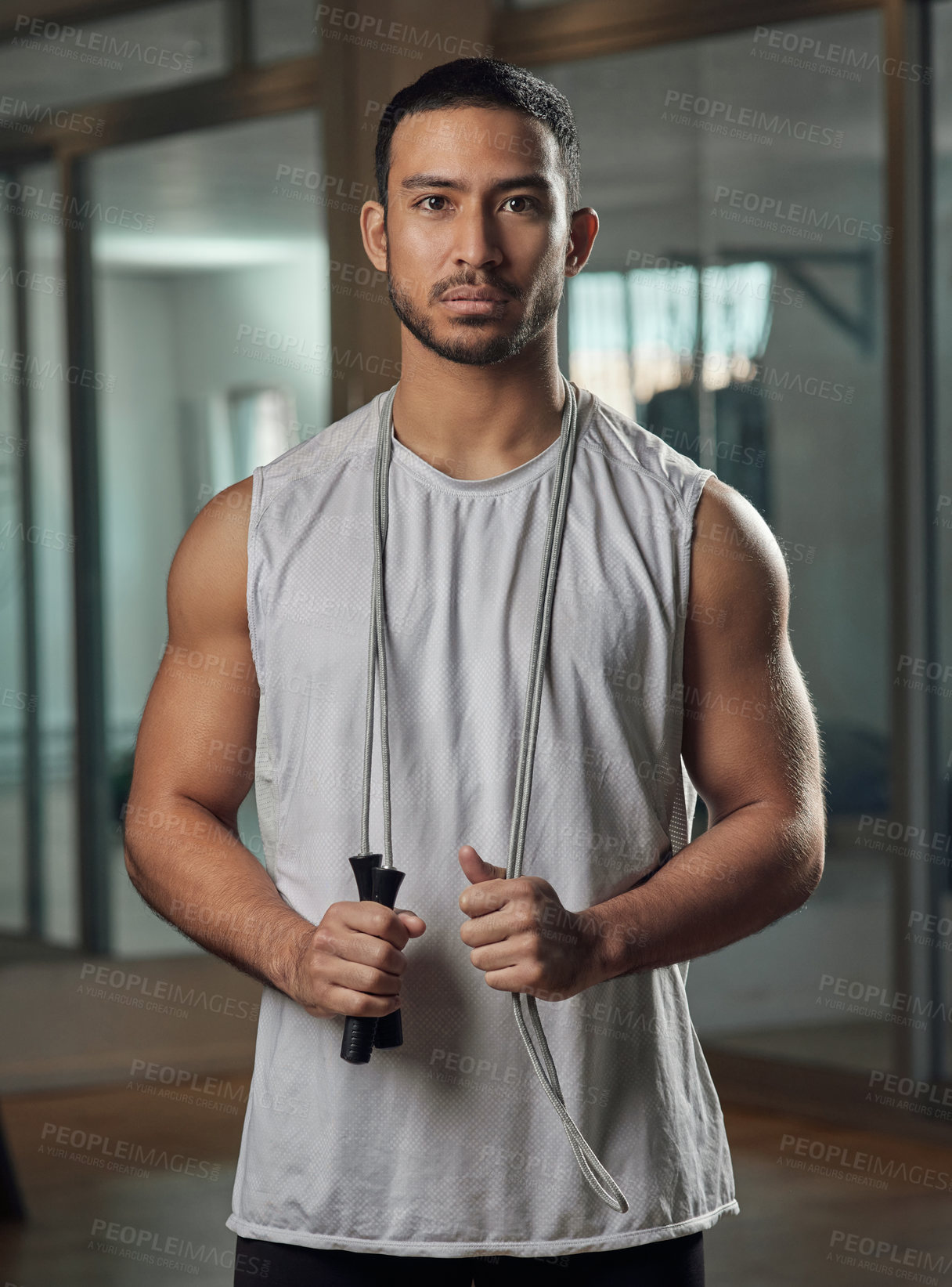 Buy stock photo Cropped portrait of a handsome young male athlete standing with a skipping rope in the gym