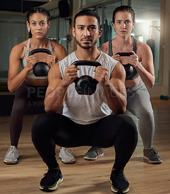 Buy stock photo Full length portrait of three young athletes working out with kettle bells in the gym