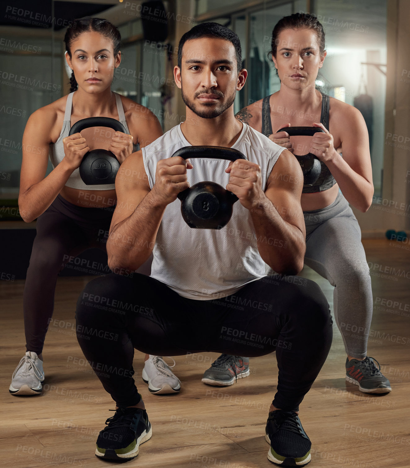 Buy stock photo Full length portrait of three young athletes working out with kettle bells in the gym