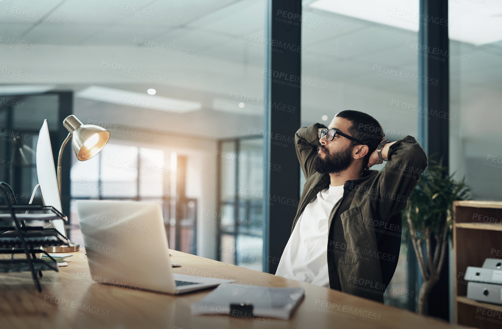 Buy stock photo Shot of a young businessman taking a break while working late at night in a modern office