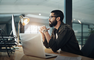 Buy stock photo Shot of a young businessman using a computer during a late night in a modern office